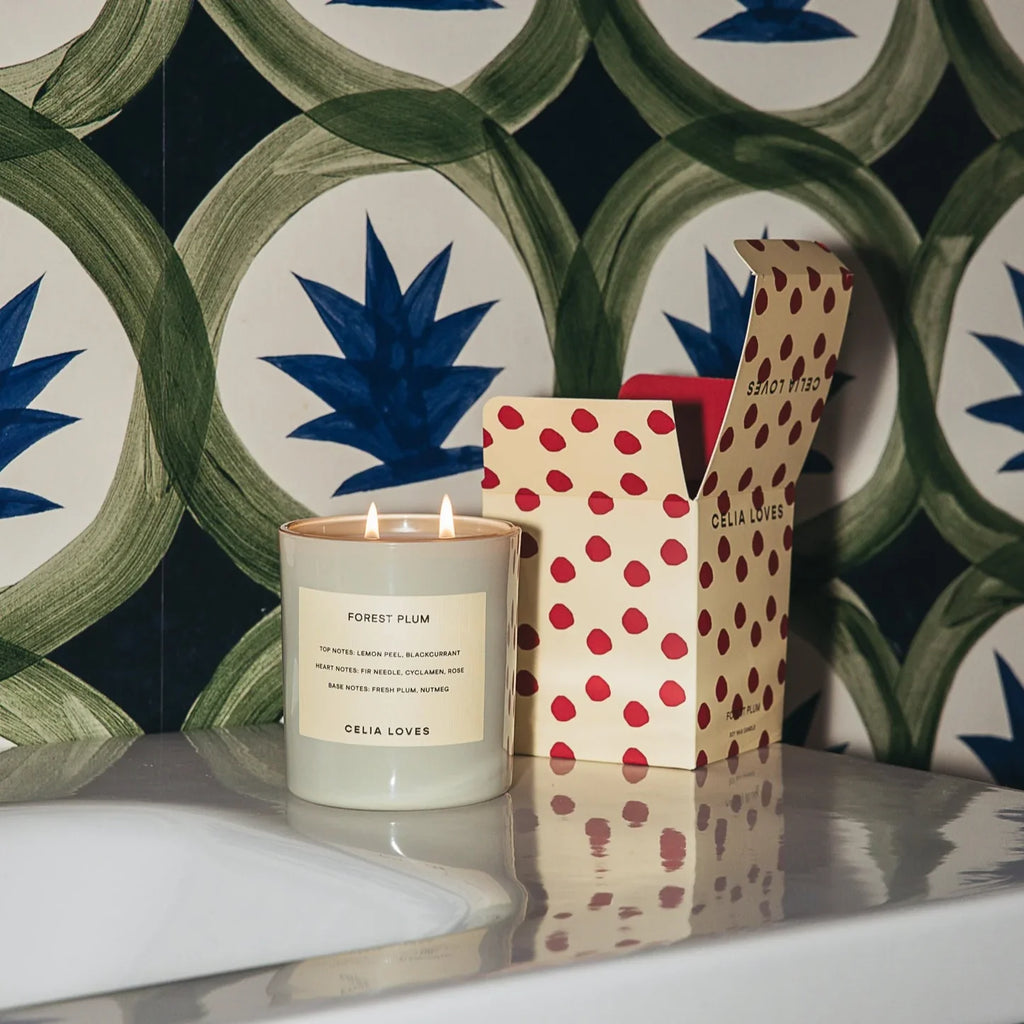 celia loves candle next to packaging box against a green and blue patterned background