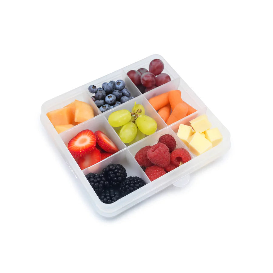 White compartmentalized container filled with a variety of fruits on a white background