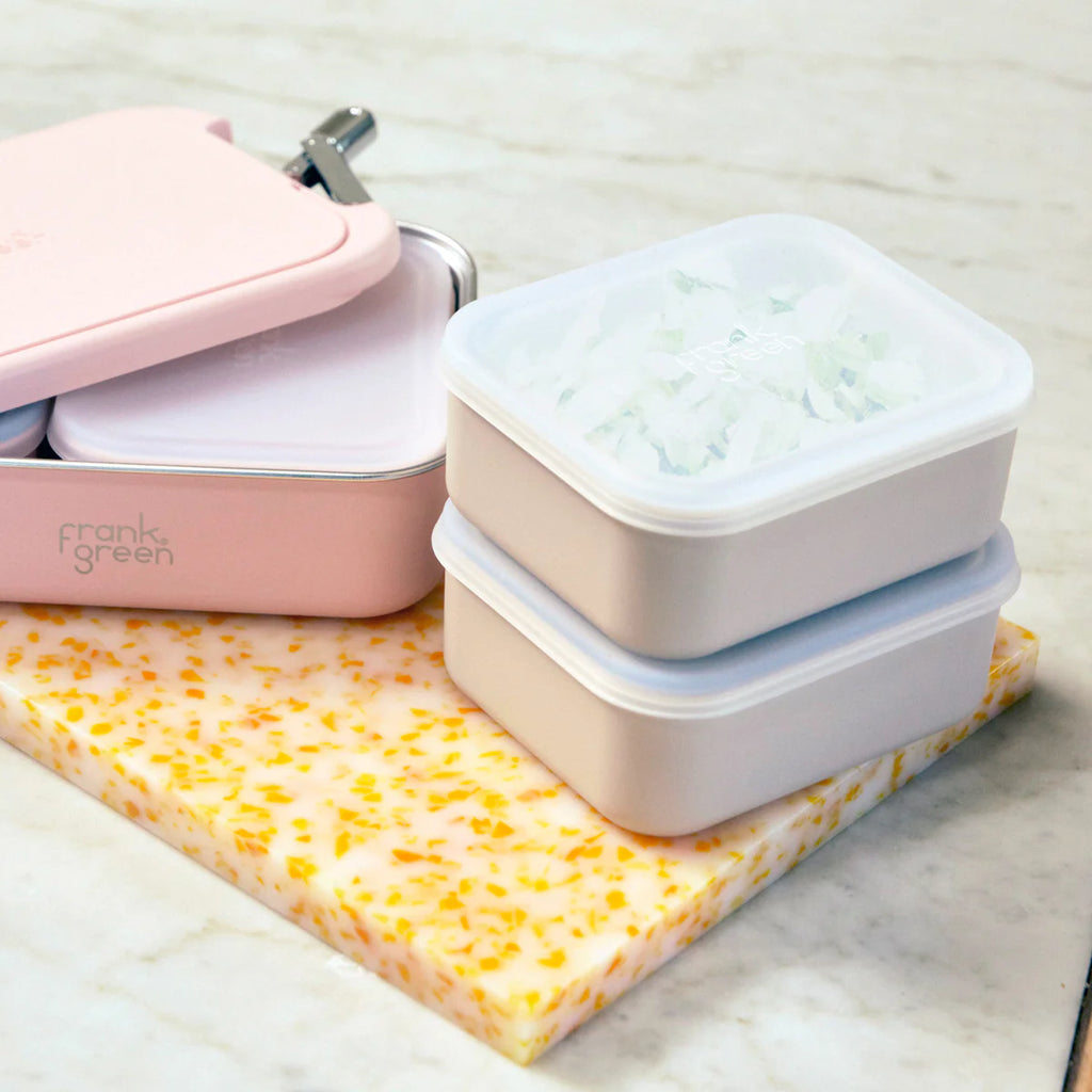Set of reusable food containers with a pink case on a light surface