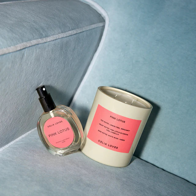 Cela Loves Pink Lotus candle and perfume bottle on a light blue surface