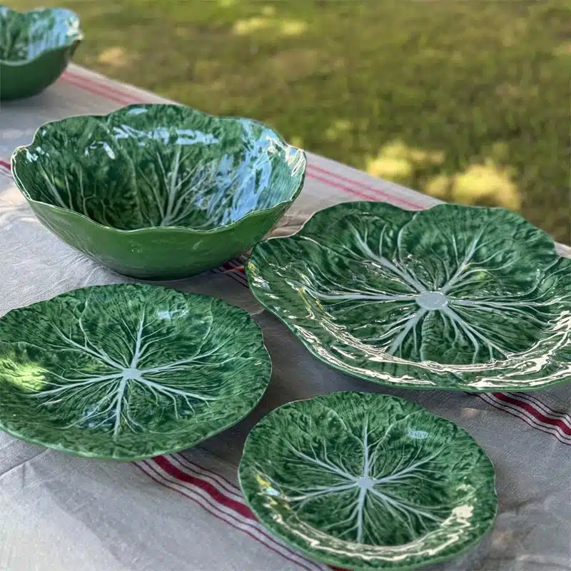 Set of green melemine  dishes with leaf design on a table outdoors.