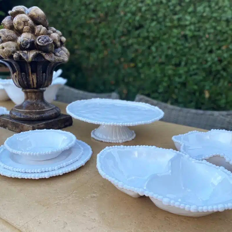 Set of white melamine dishes on a wooden surface with decorative elements.