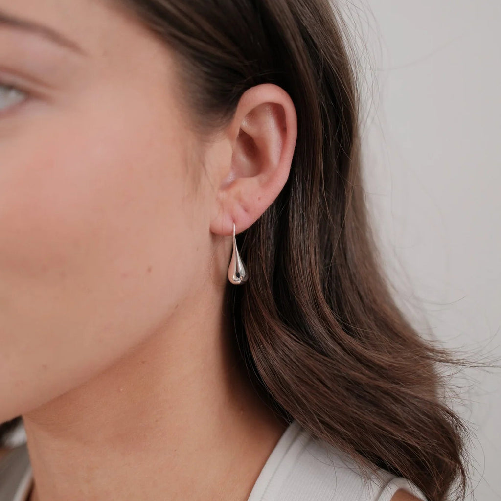 Close-up of a person wearing a silver earring with a white background
