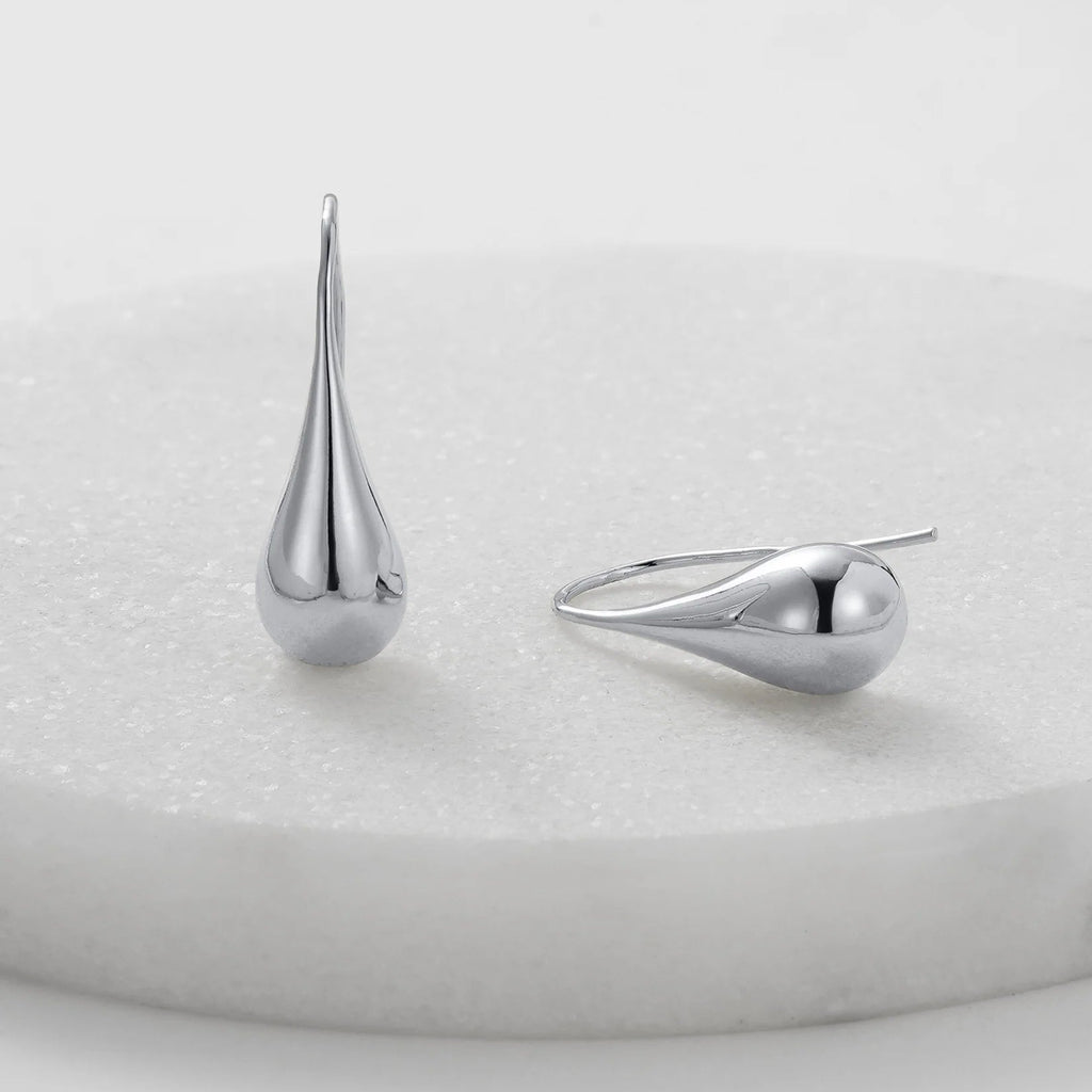 Two silver teardrop-shaped earrings on a light gray background