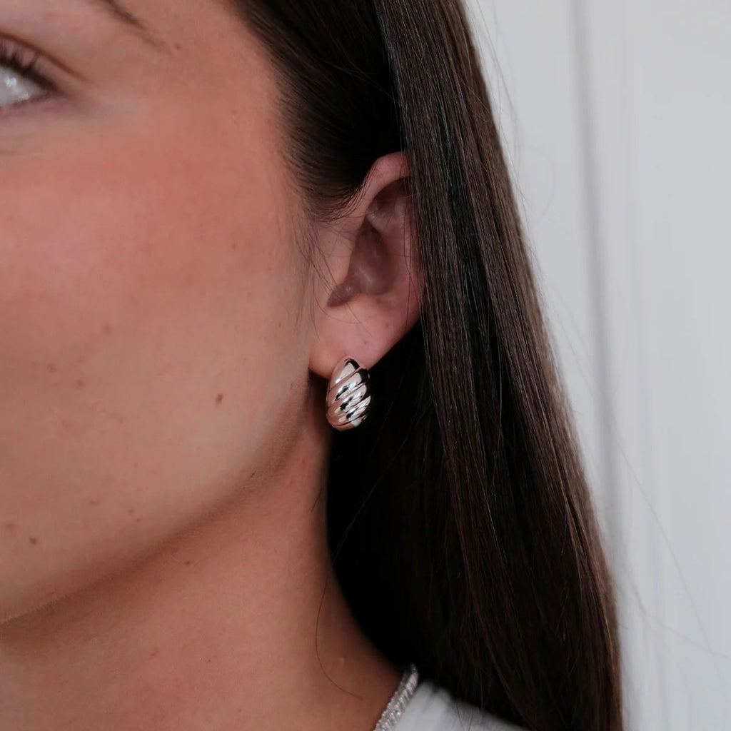 Close-up of a person wearing a silver earring with a white background