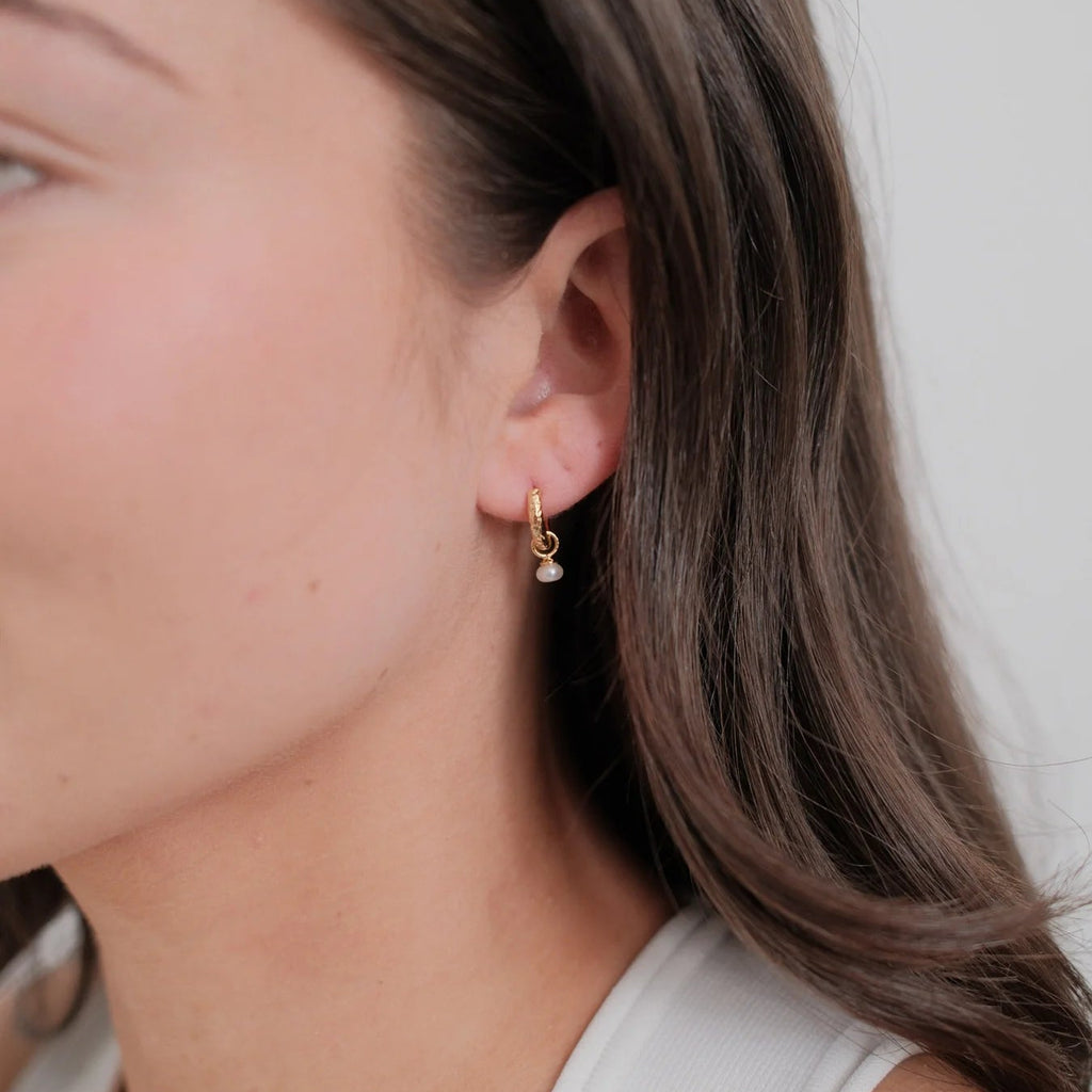 Close-up of a person wearing gold earrings with a white background