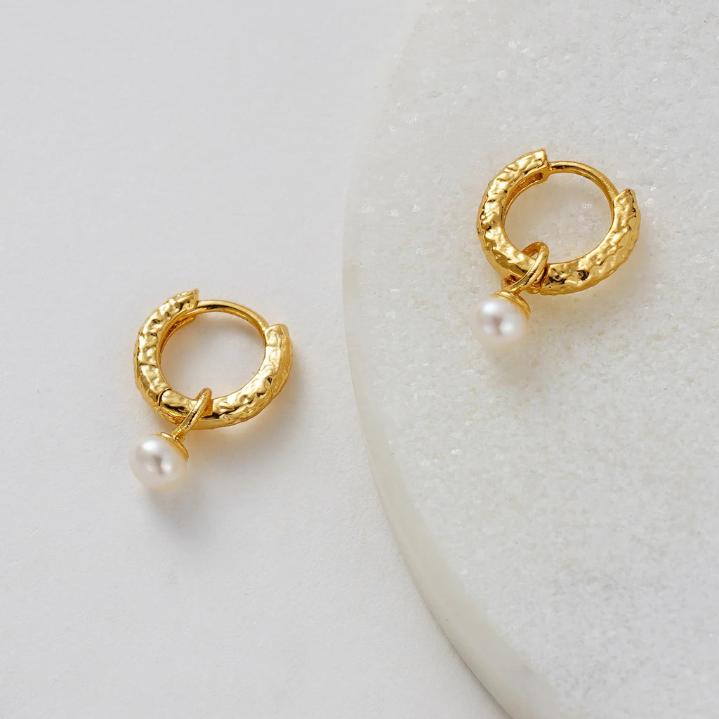 Gold hoop earrings with pearls on a white background
