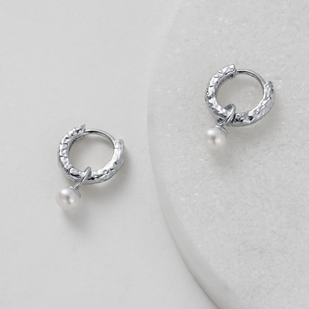Silver hoop earrings with pearls on a light gray background