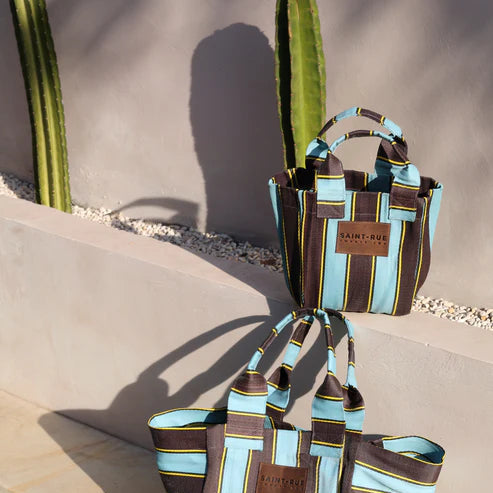 Striped handbag with visible brand name on a reflective surface near water