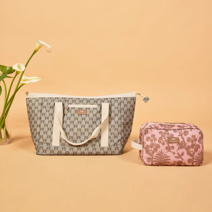 Gray patterned tote bag with white handles and a smaller floral pouch on a beige background.