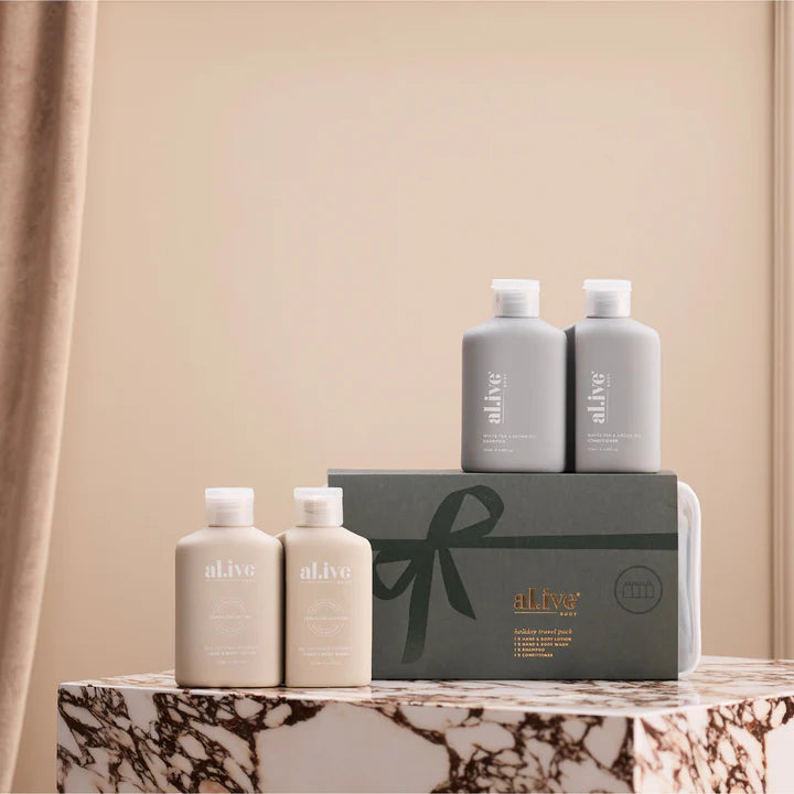 Set of 'alive' skincare products on a marble surface with a beige curtain background