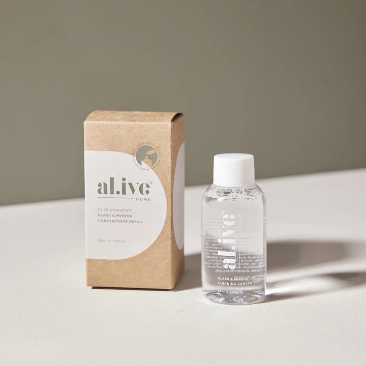 Clear bottle with white cap and 'alive' label next to a cardboard box on a light surface.
