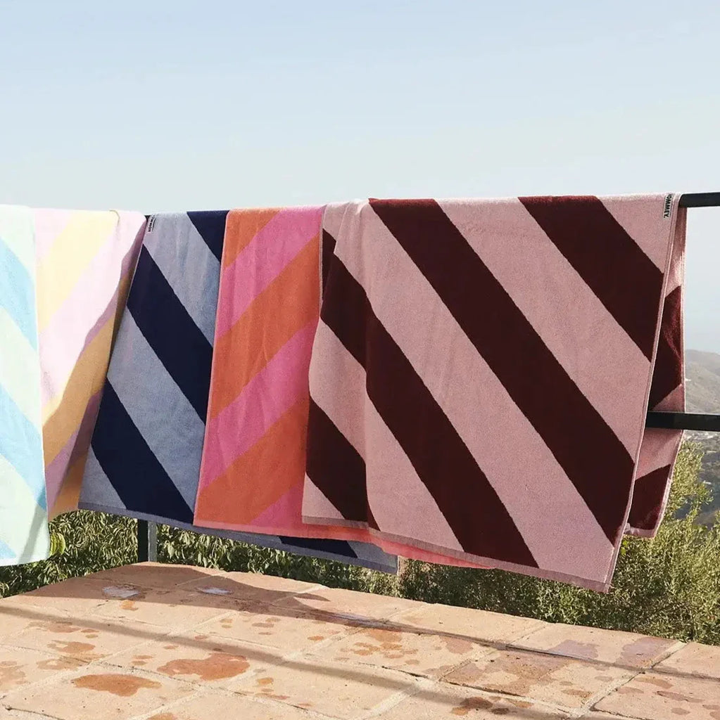 Colorful striped towels hanging on a clothesline with a scenic background