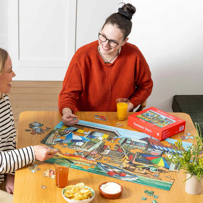 two people sitting at a table doing a jigsaw puzzle