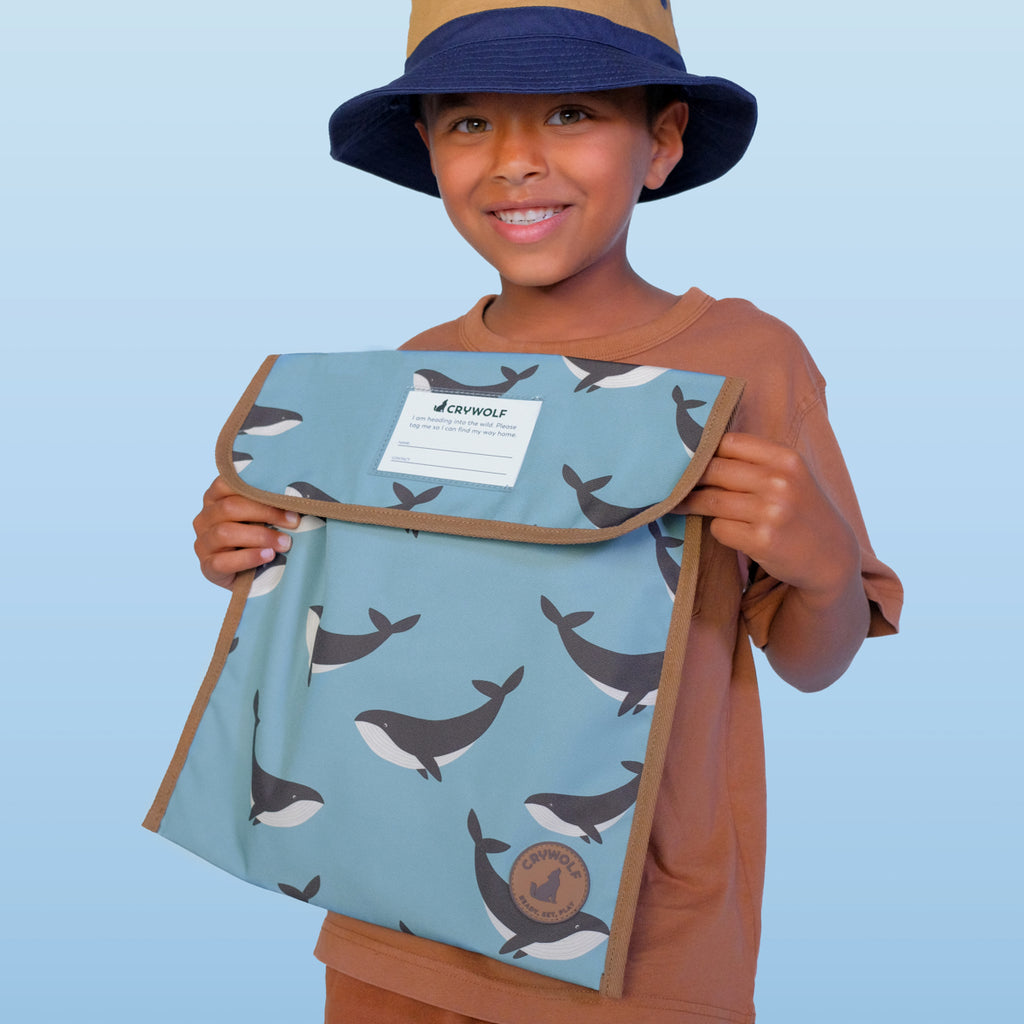 Child holding a bag with whale pattern against a light blue background