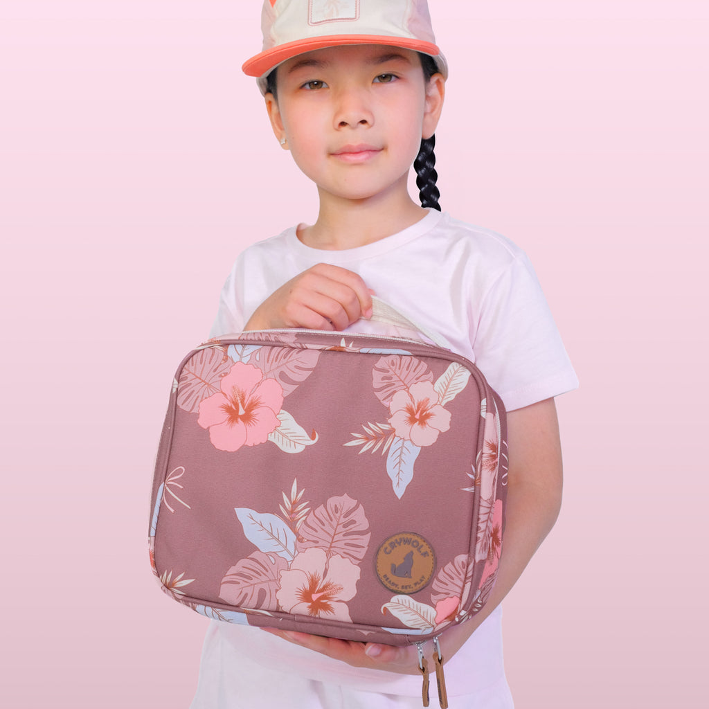 Child holding a floral-patterned bag against a pink background
