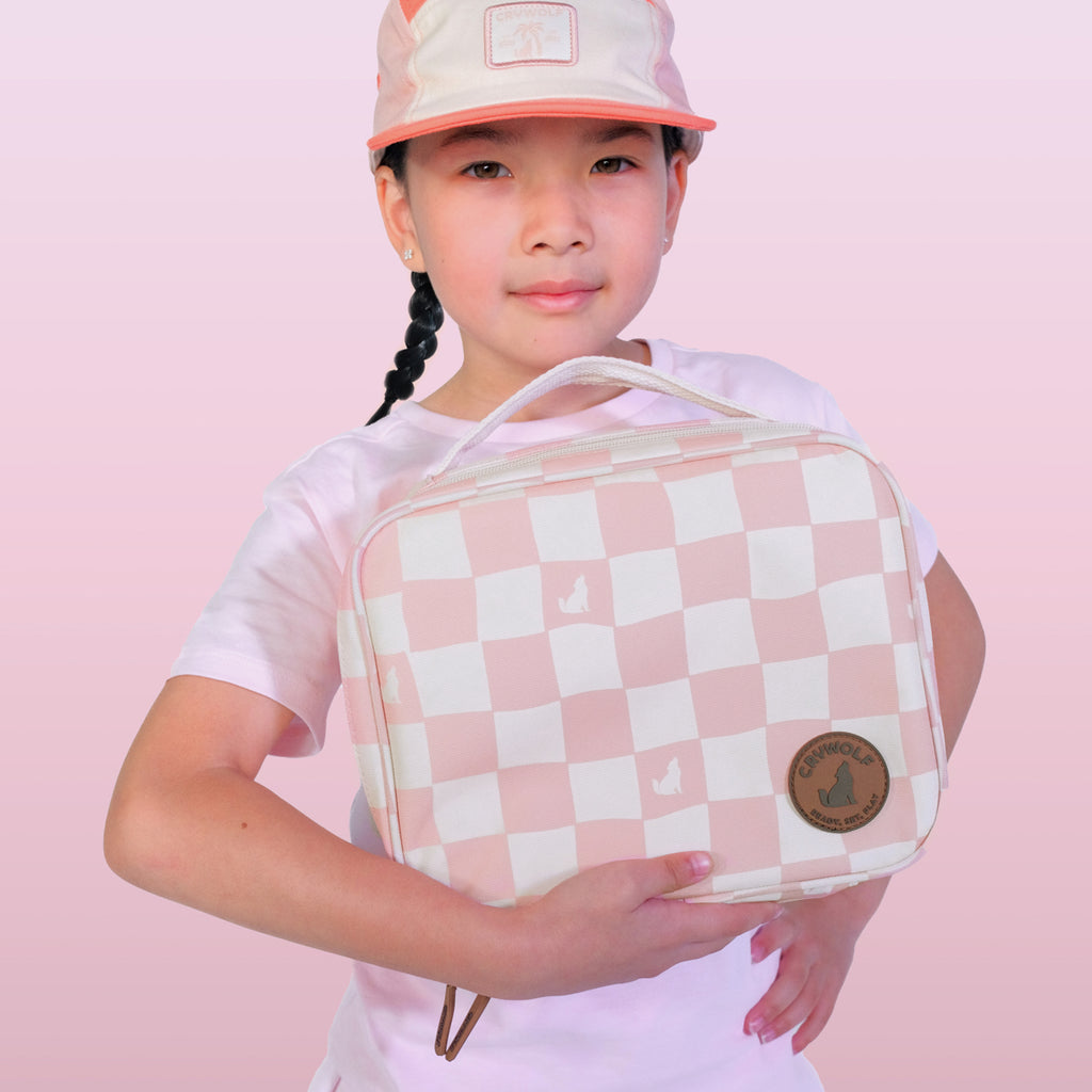 Child holding a pink and white checkered bag against a pink background
