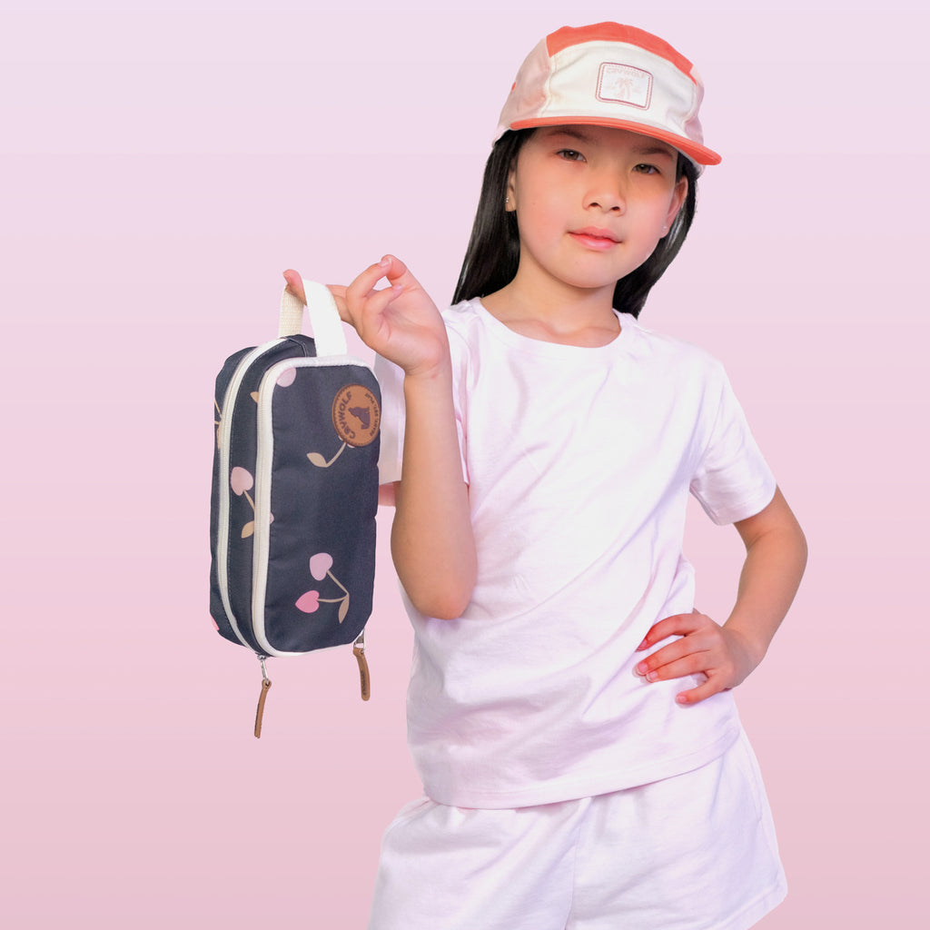 Child holding a small bag with a cherry design on a pink background