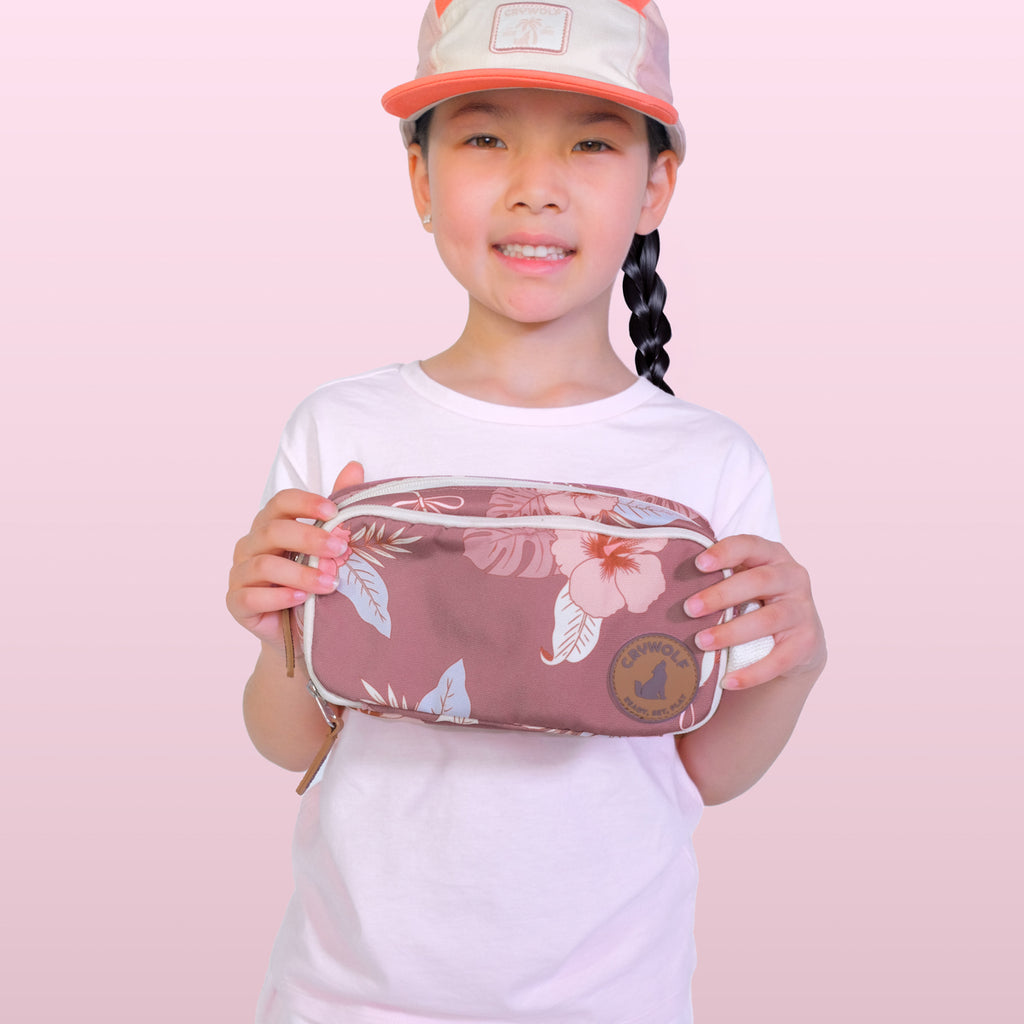 Child holding a pink floral pouch against a pink background