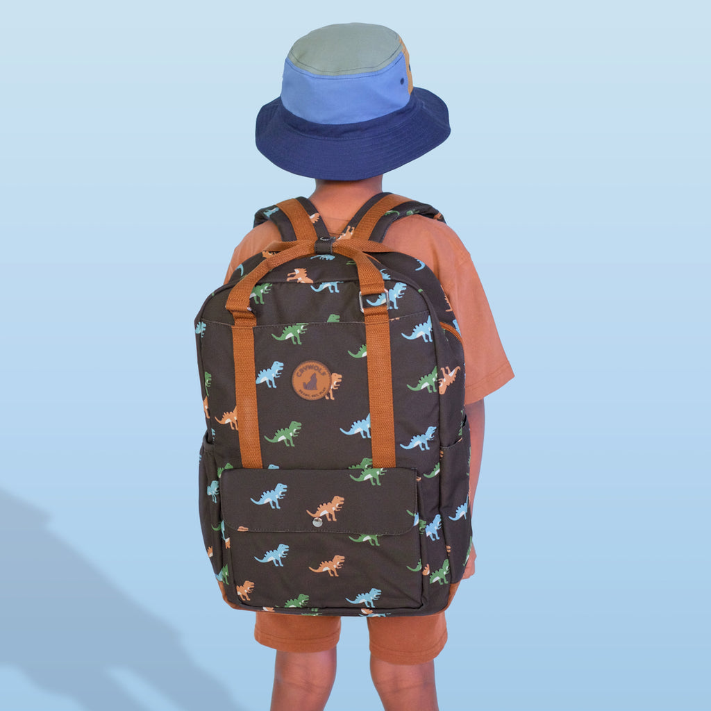 Person wearing a dinosaur-patterned backpack and blue bucket hat on a light blue background
