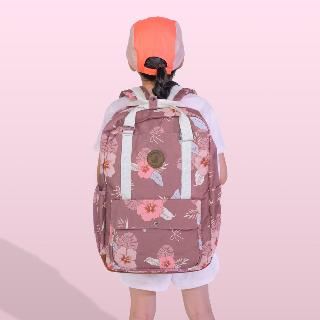 Person wearing a pink floral backpack on a light pink background