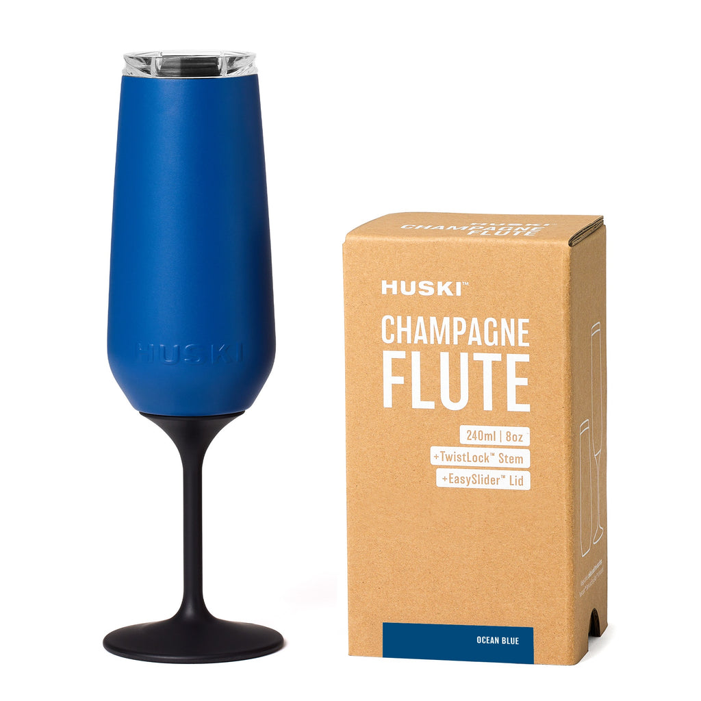 Blue champagne flute with black stem next to its packaging box on a white background