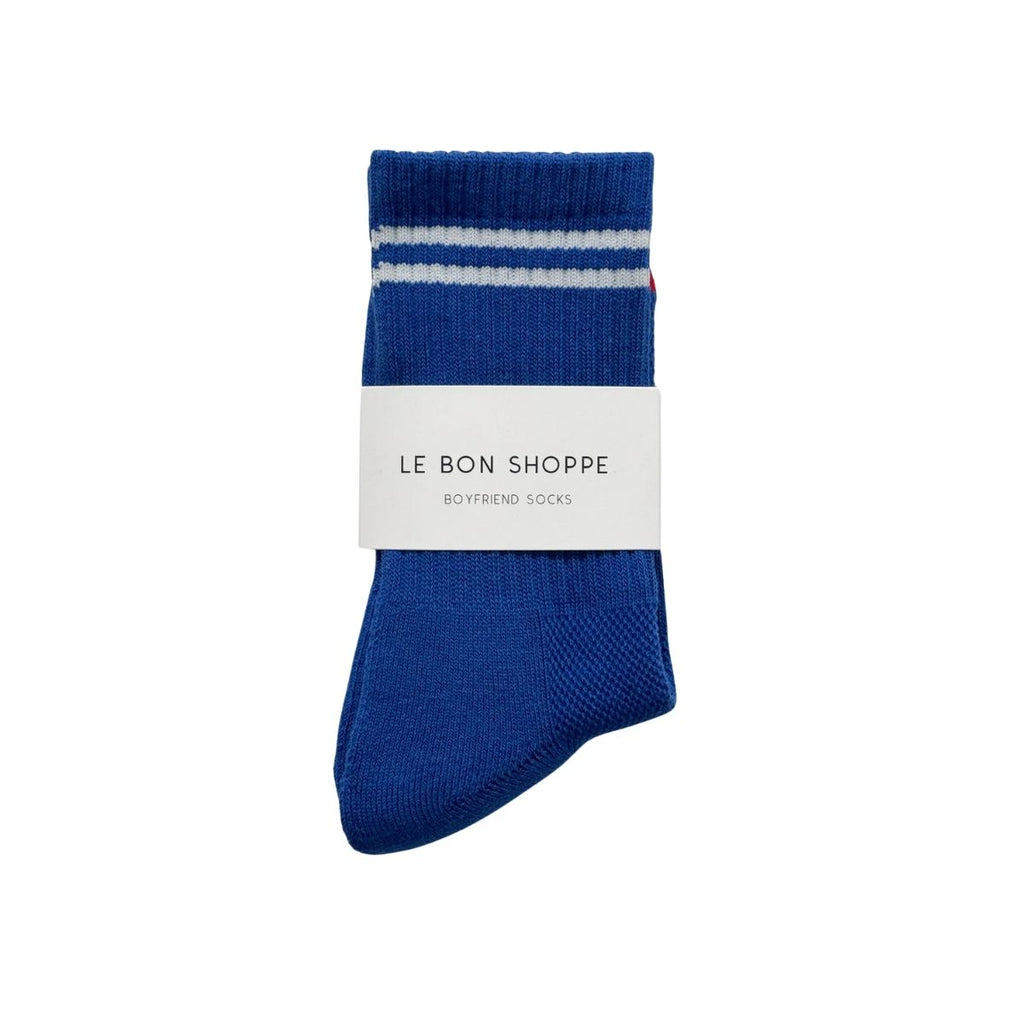 Blue sock with white stripes and 'Le Bon Shoppe' label on a white background