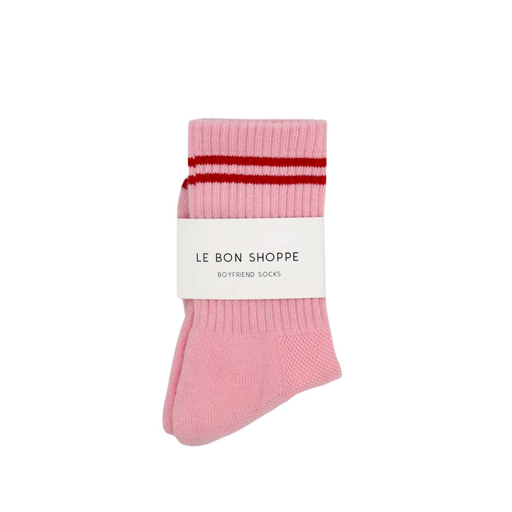 Pink sock with red stripes and 'Le Bon Shoppe' label on a white background