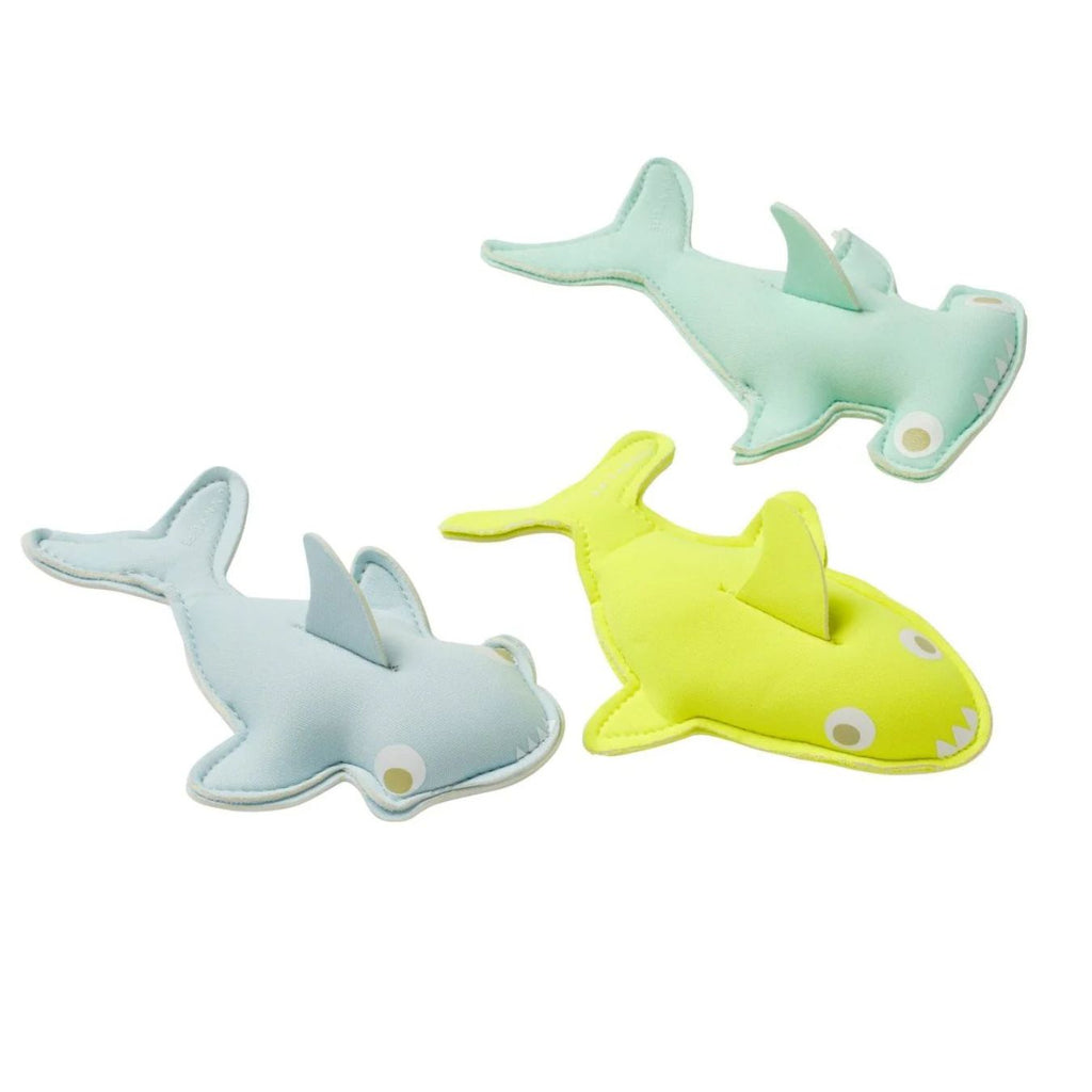 Three shark-shaped toys in green, blue, and yellow on a white background