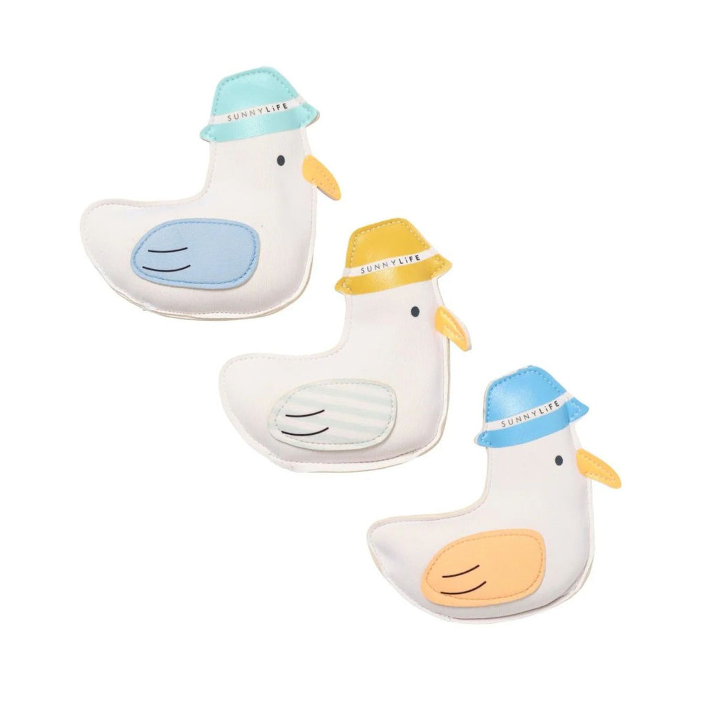 Three seagill-shaped toys with colorful hats on a white background