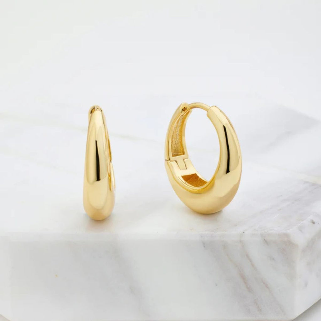 Gold hoop earrings on a marble surface