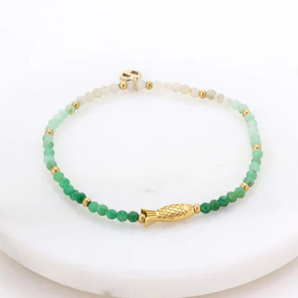 Green beaded bracelet with gold fish clasp on a white background