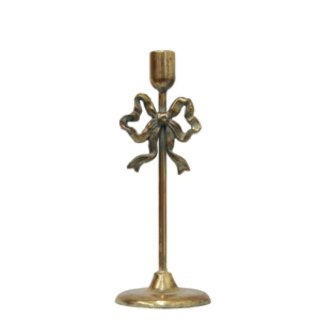 Brass candle holder with bow design on a white background