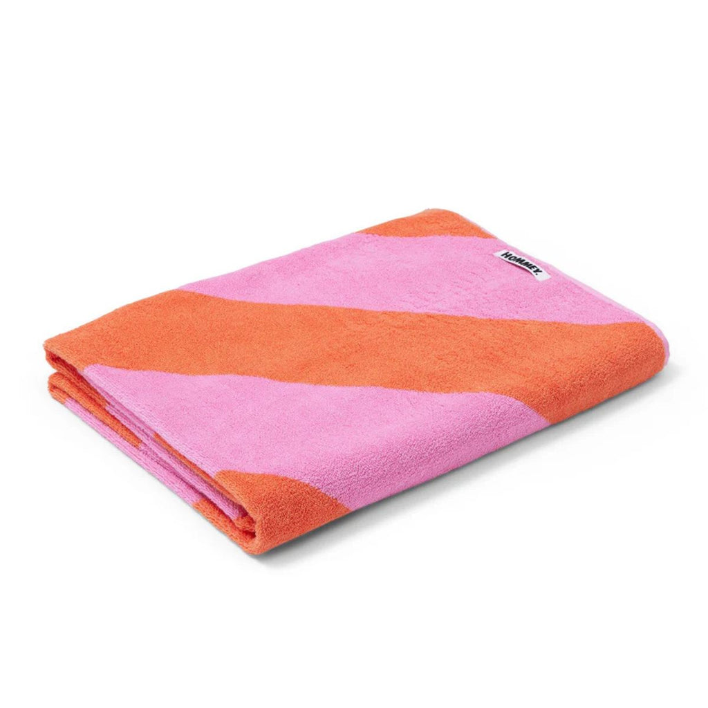 Folded pink and orange towel with a brand label on a white background