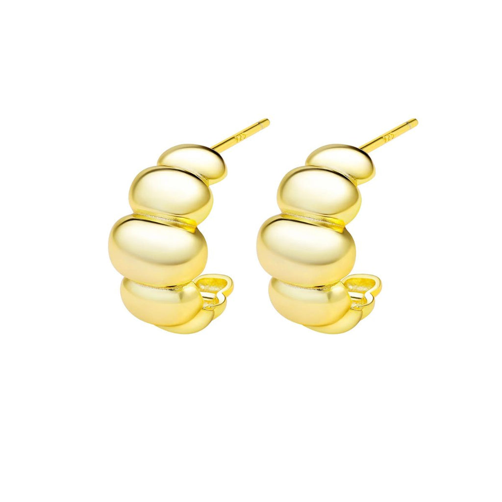 Gold huggie earrings against a white background