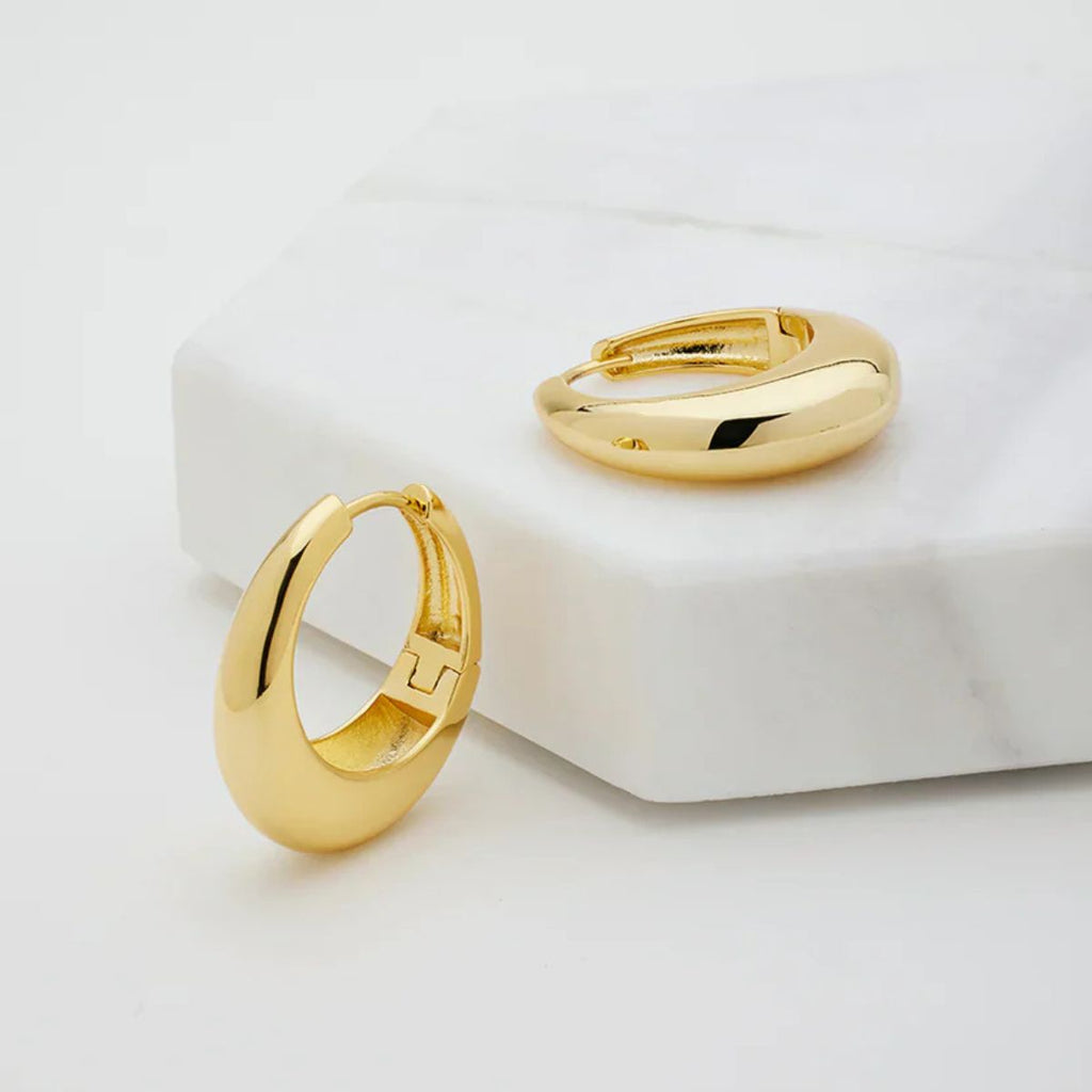 Gold hoop earrings on a white surface