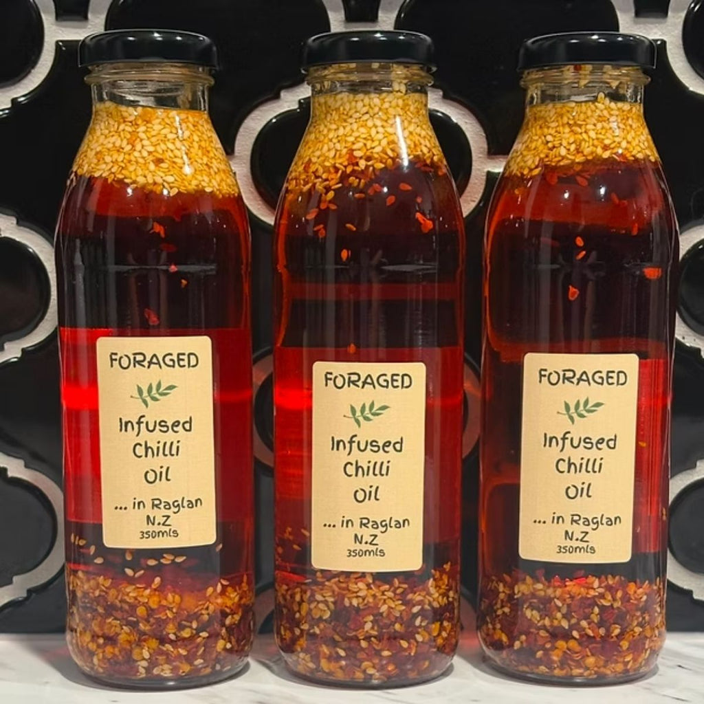 Three bottles of Foraged Infused Chilli Oil with visible labels on a dark background.