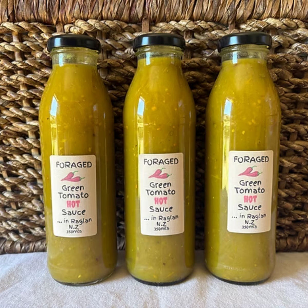 Three bottles of Foraged Green Tomato Hot Sauce on a woven basket background