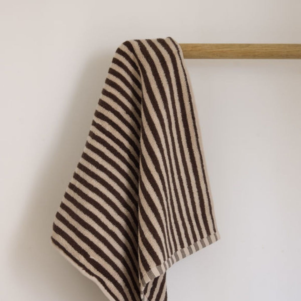 Striped towel hanging on a wooden rack against a plain background
