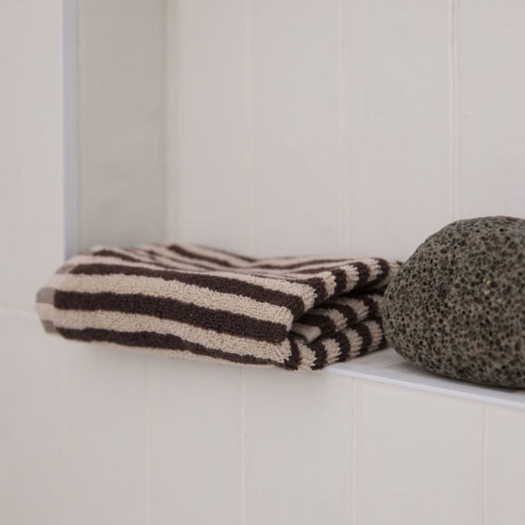 Folded striped towel and textured stone on a white surface