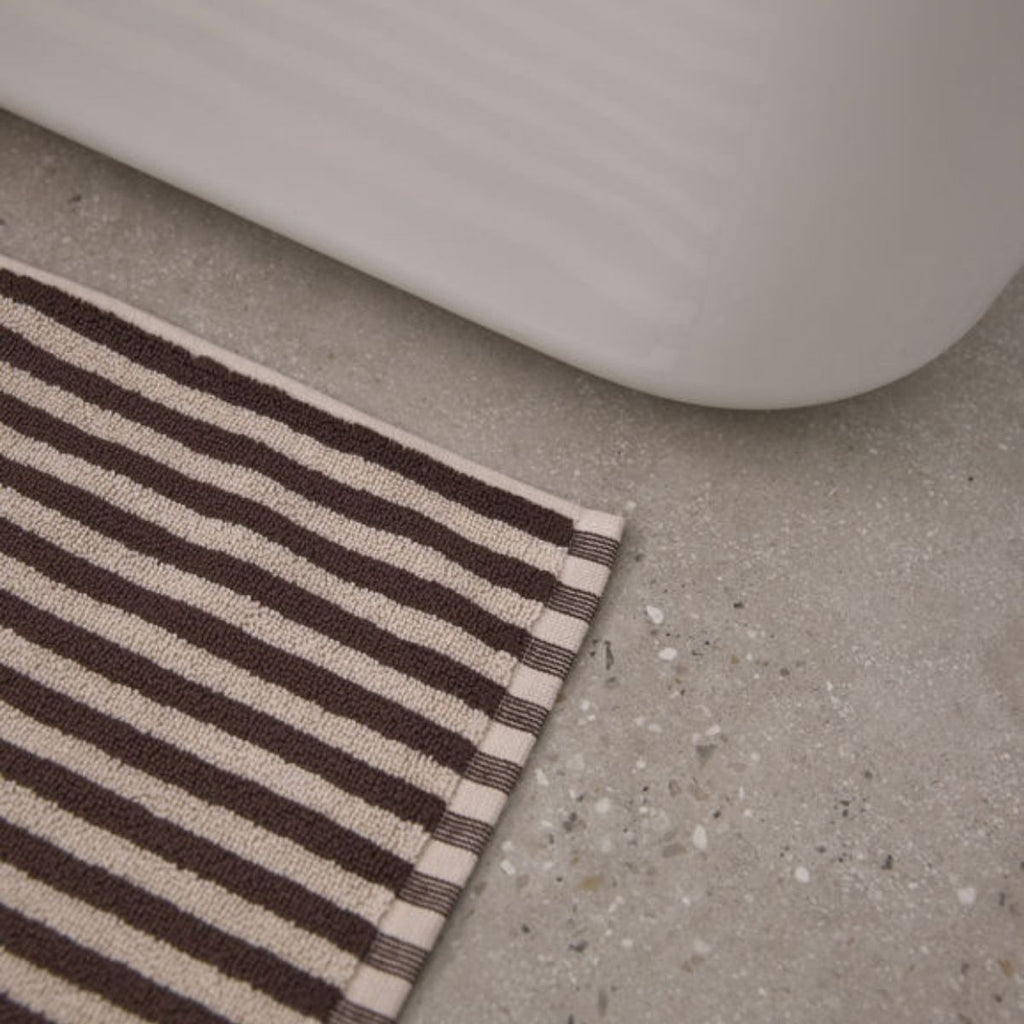 Striped rug on a concrete floor with a white baseboard.