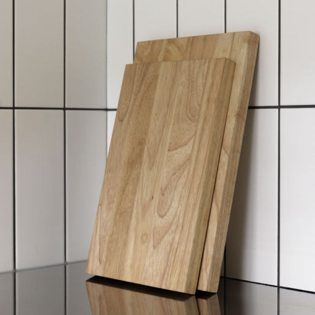 Two wooden cutting boards leaning against a tiled wall.
