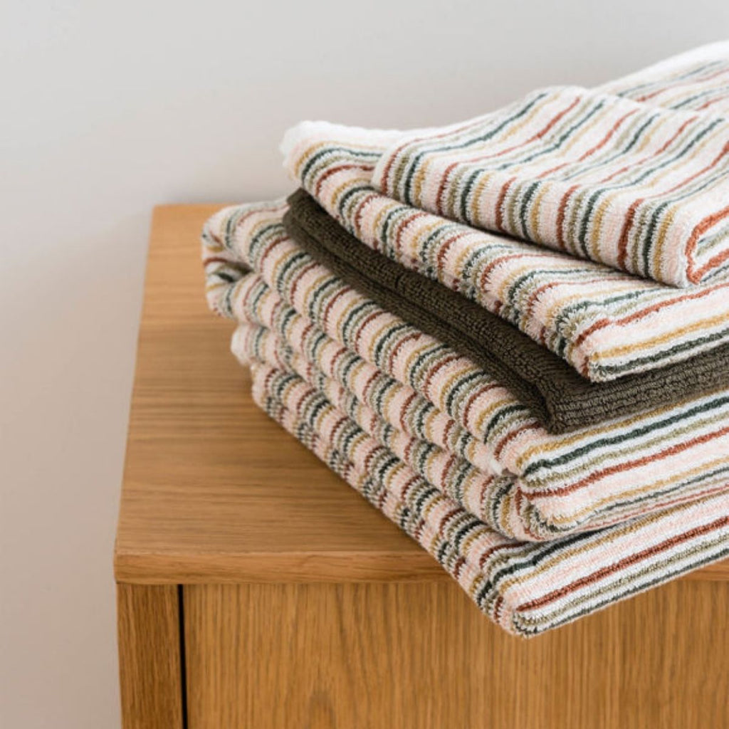 Folded striped blanket on a wooden surface with a neutral background