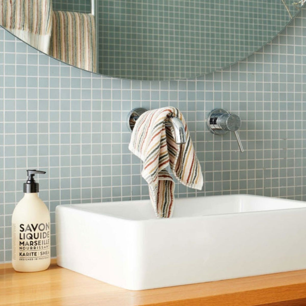 Bathroom with a sink, mirror, and soap dispenser and hand towel over the tap