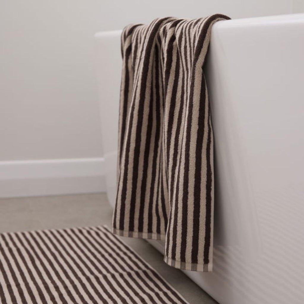Striped towel draped over a white bathtub in a bathroom setting