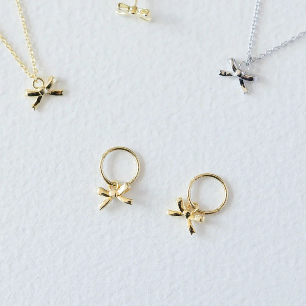 Gold bow-shaped earrings on a light gray background