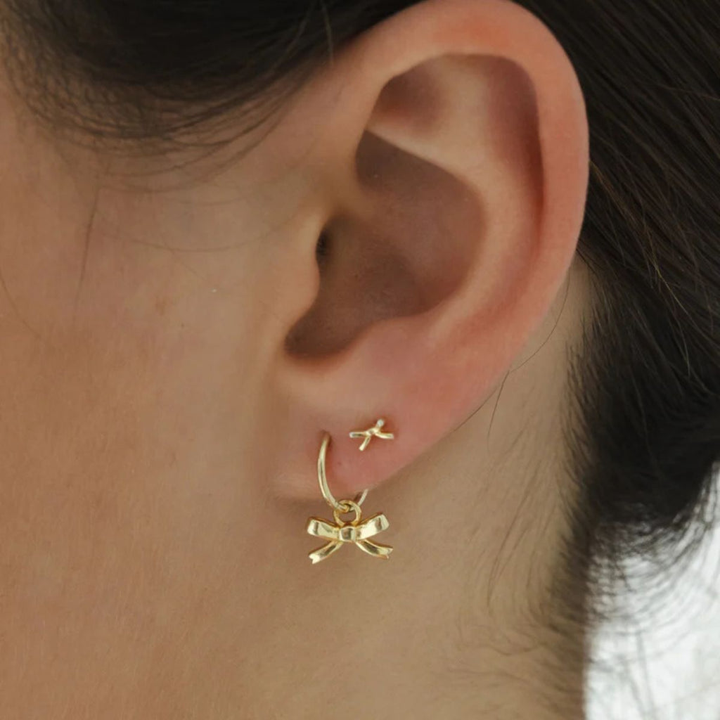Gold bow-shaped earring worn by a person