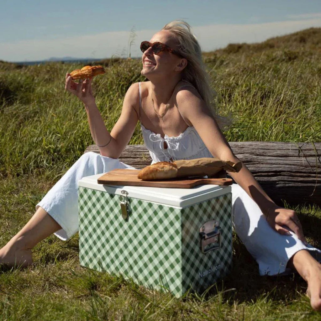Woman sitting outdoors with a picnic basket, eating bread.