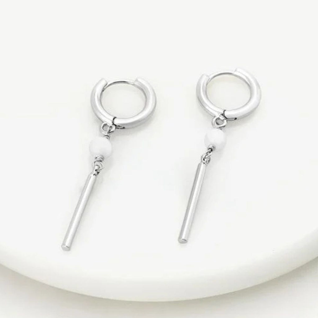 Pair of silver hoop earrings with dangling bars on a white plate.