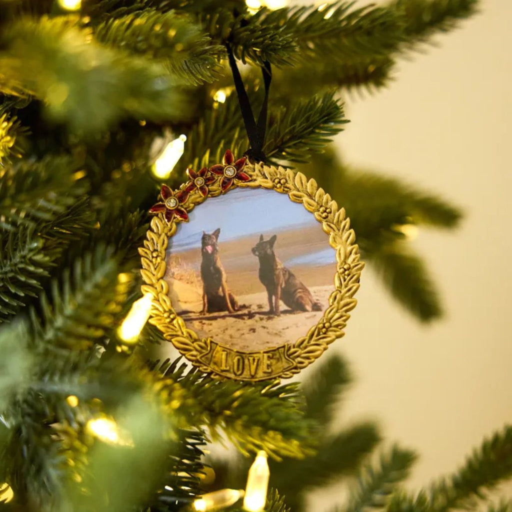 Decorative ornament with two dogs on a beach, hanging on a Christmas tree.